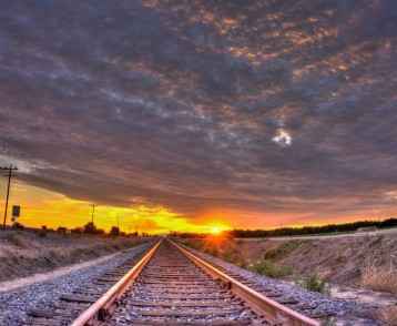 Sunset rays streak from below the cirrocumulus clouds over train